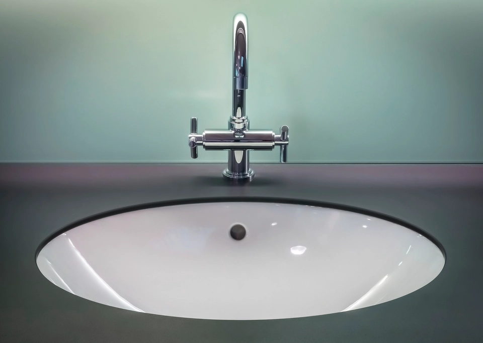 A clean white sink with a polished chrome tap