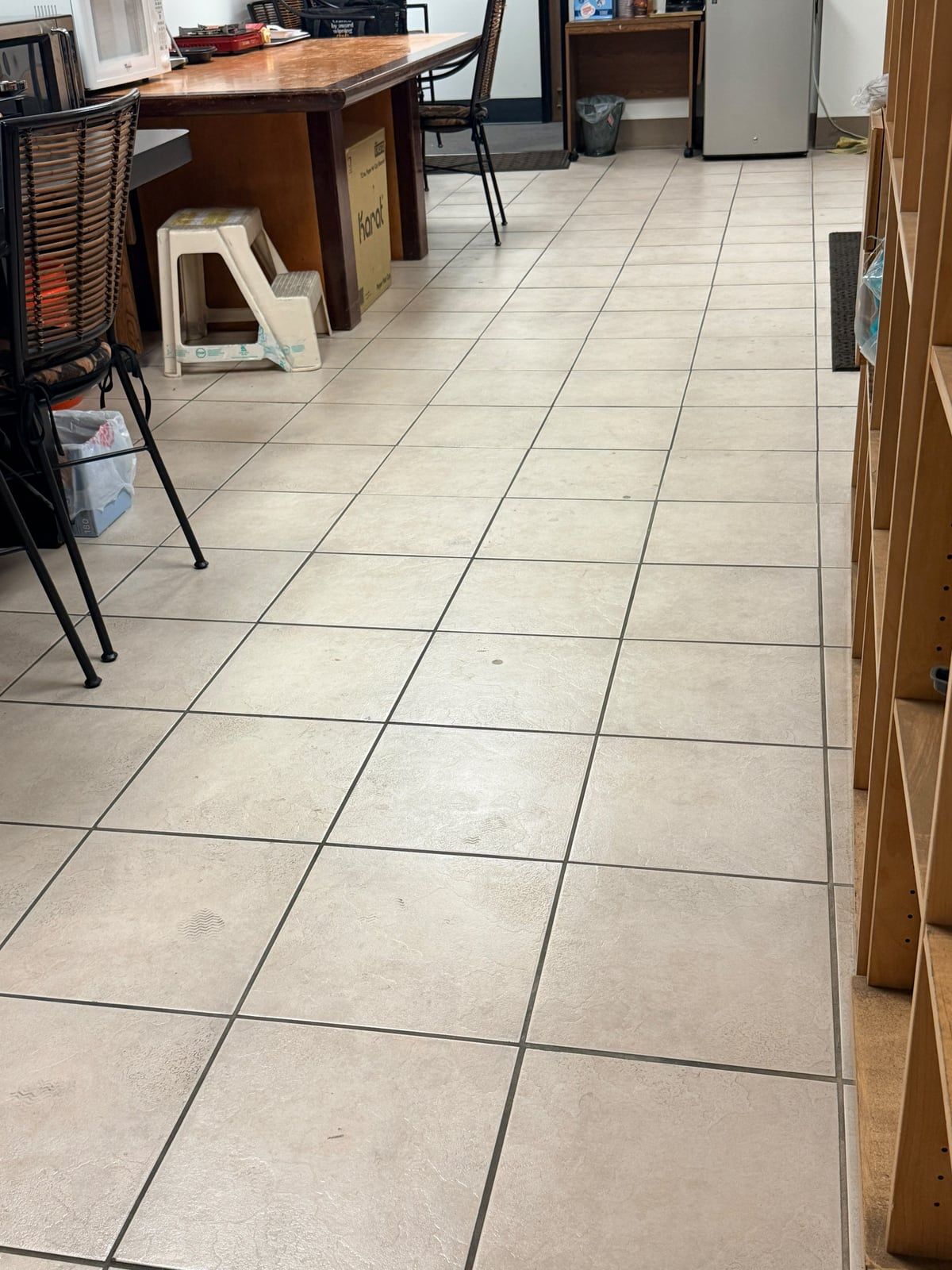 A breakroom tile floor with scuffs and small dark spots
