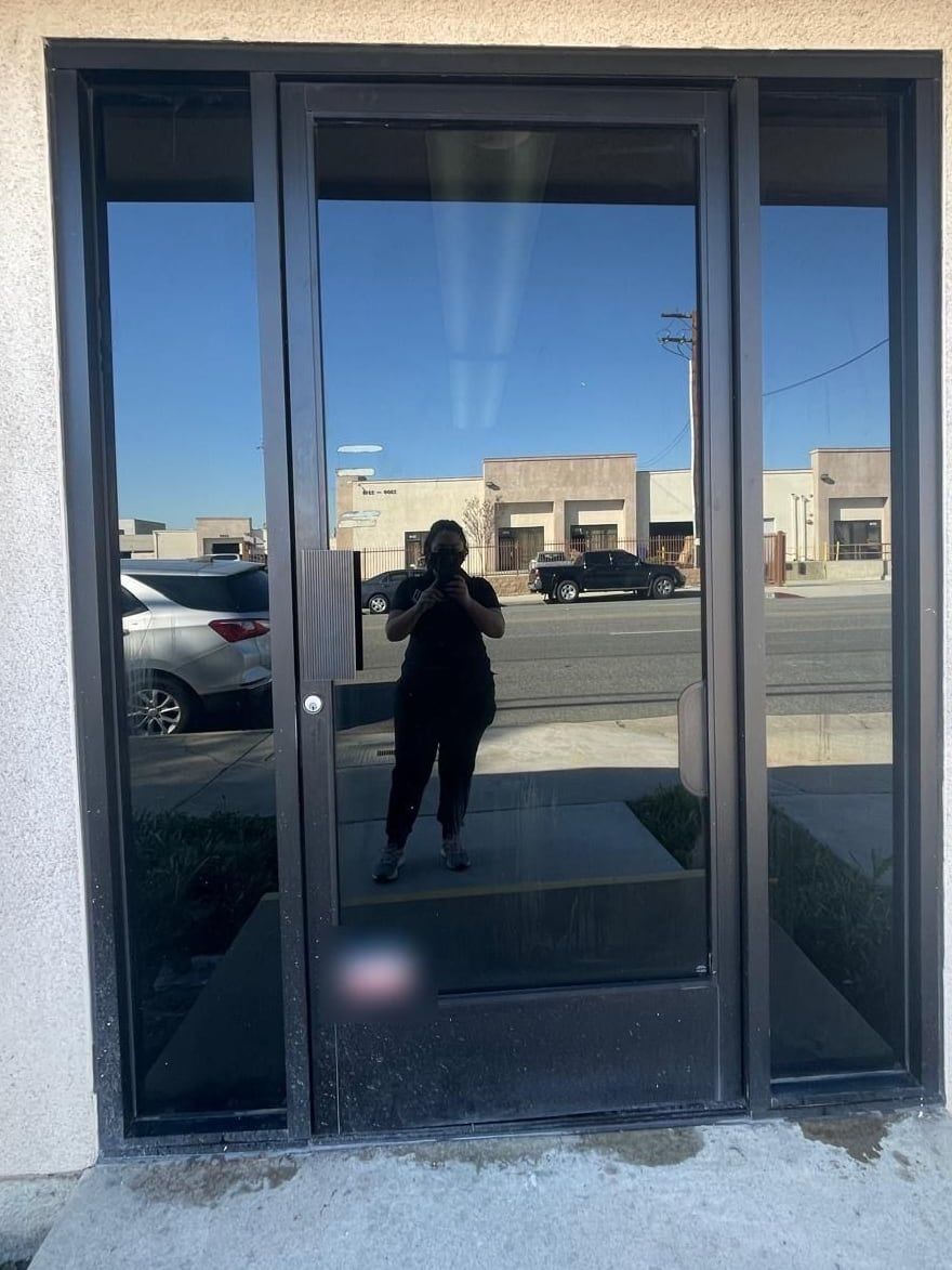The glass entry door, clean and clearly reflecting the street and the sky