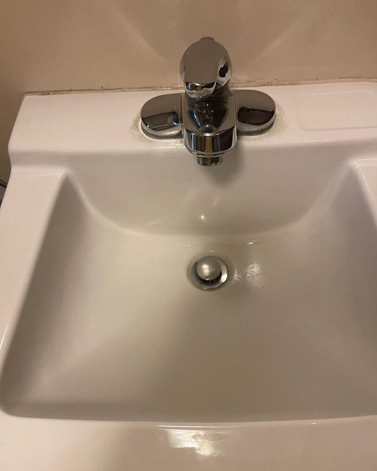 A close view of a clean white sink and polished chrome tap