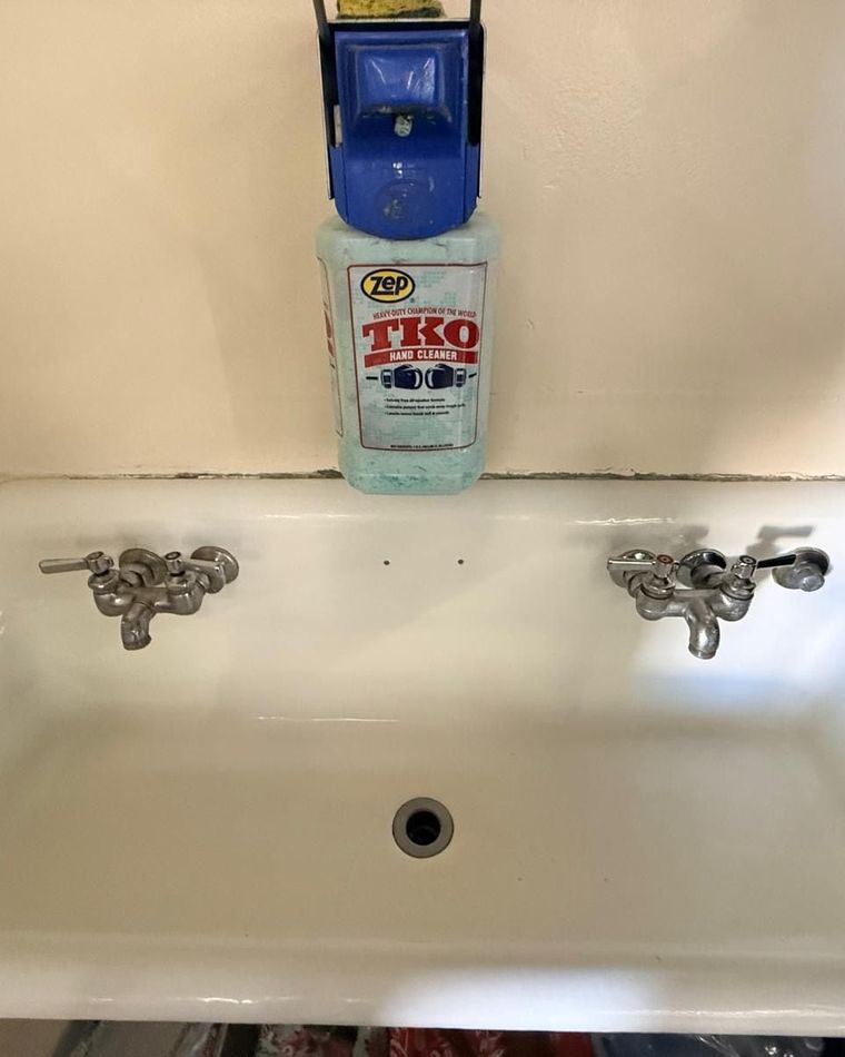 A long white utility sink with two taps, fully clean